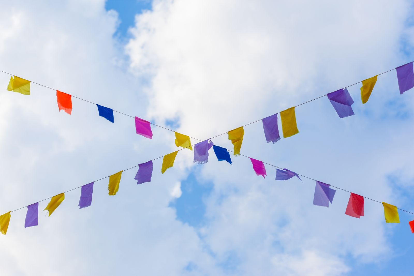 Colorful festival flags strung across a clear blue sky, creating a festive atmosphere.